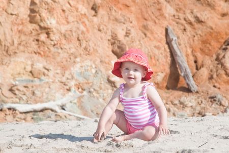 Cute Caucasian baby girl playing with the sand on the beach.の写真素材