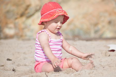 Cute Caucasian baby girl playing with the sand on the beach.の写真素材