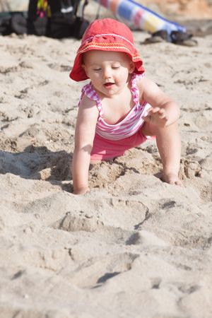 Cute Caucasian baby girl playing with the sand on the beach.の写真素材
