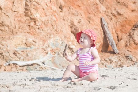 Cute Caucasian baby girl playing with the sand on the beach.の写真素材