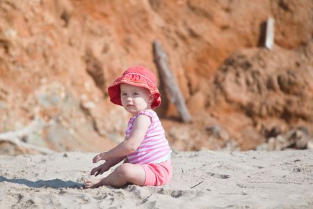 Cute Caucasian baby girl playing with the sand on the beach.の写真素材