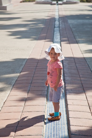 Cute little European toddler girl walking along the line.の写真素材