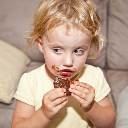 Cute little European toddler girl enjoying chocolate cookie.の写真素材