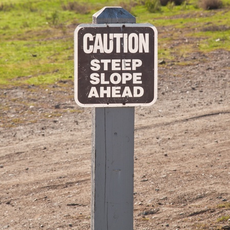 Metal warning informational sign on a wooden pole next to trail in the park.の写真素材