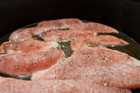 Frying juicy tenderloin chicken breasts on black pan.の写真素材