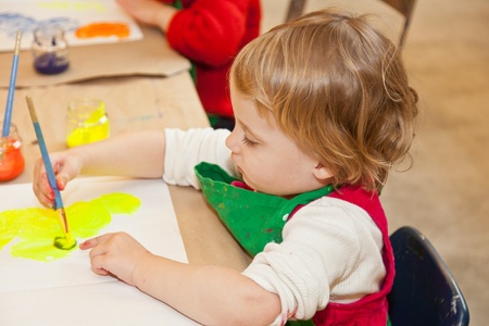 Cute little baby girl having fun painting at art classの写真素材
