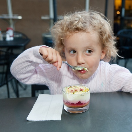 Eating CrÃ¨me brÃ»lÃ©e with great enthusiasm in a coffee shop.の写真素材