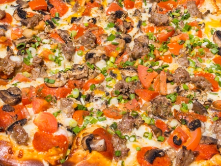 Thin crust pizza with various toppings and melted cheese.の写真素材