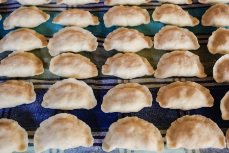 Rows of raw pierogis on cloth ready for cooking.