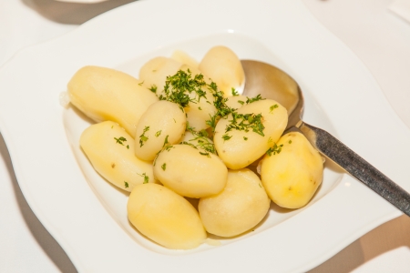 Fresh cooked potatoes with cut parsley on a white plate.の写真素材
