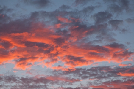 Orange sunset behind bright lit clouds, blue sky over northern California.