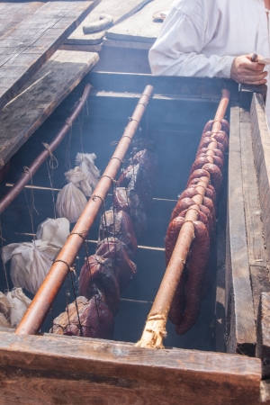 Ancient wooden smoker and racks with hot smoked sausages and meat.の写真素材