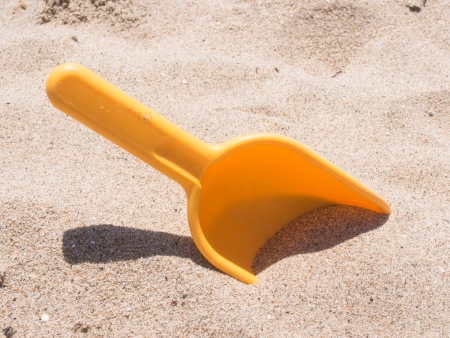 Plastic beach shovel in sand on a beach.の写真素材