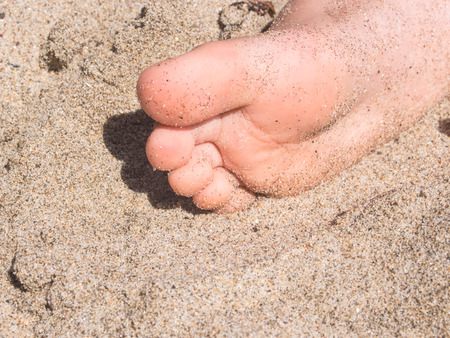 One foot in sand on a beach on sunny day.の写真素材