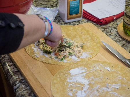 Rolling enchiladas with corn tortillas on large wooden cutting boardのeditorial素材