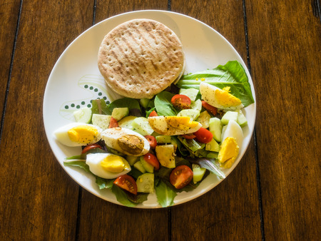 Crab cake sandwich with salad made of organic romaine lettuce with cucumber, tomatos and egg.