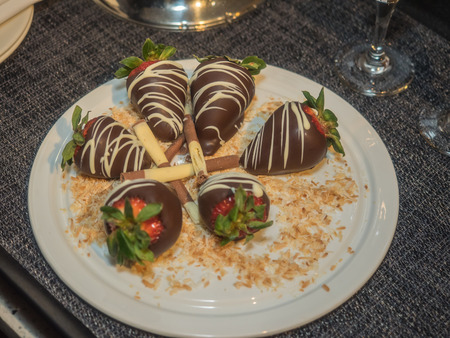 Chocolate covered strawberries with coconut flakes on a plateの写真素材