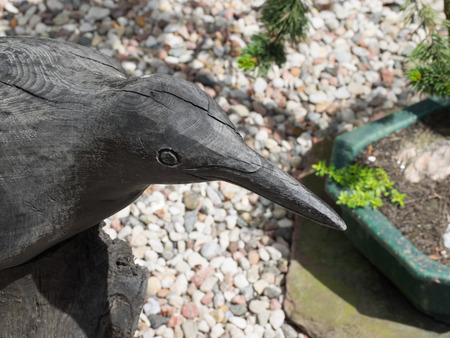 Wooden sculpture of black raven in a garden.の写真素材