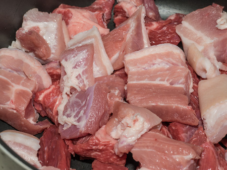 Pieces of raw beef and pork bacon in a pot ready to cook a broth.の写真素材