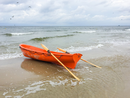 Orange row boat on a Baltic Sea beach in summerの写真素材