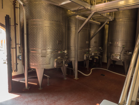 Metal wine fermentation containers in vineyard.