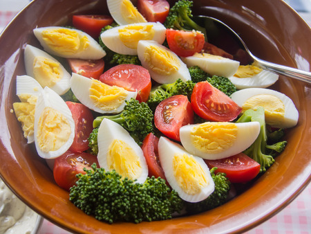 Broccoli tomato egg salad in wooden bowl on party table.の写真素材