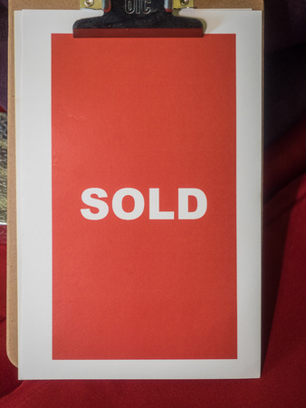 Clipboard holding red sold sign during auctionの写真素材