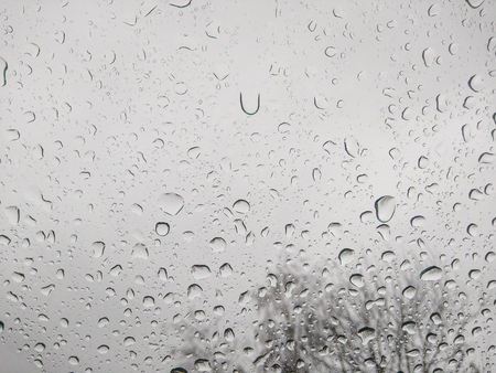 Raindrops on windshield with blurry view behind.の写真素材