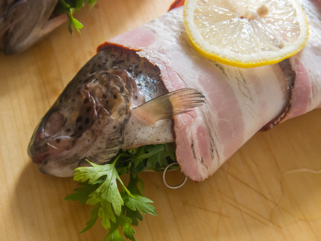 Delicate fresh trout are seasoned with a lemon-butter sauce and wrapped with bacon.の写真素材