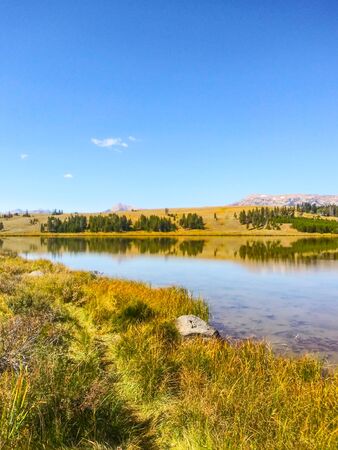 A calm Swan Lake, in the northwest corner of Yellowstone, reflects mountains in the Gallatin Range.の写真素材