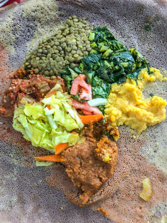 Ethiopian cuisine characteristically consists of vegetable and often very spicy meat dishes. This is usually in the form of wat, a thick stew, served atop injera, a large sourdough flatbread, which is about 50 centimeters (20 inches) in diameter and made out of fermented teff flour. Ethiopians eat most of the time with their right hands, using pieces of injera to pick up bites of entrÃ©es and side dishes.の写真素材