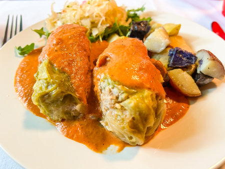 A delicious plate of cabbage rolls served with a side of potatoes and sauerkraut. This dish appears to be savory and rich with a flavorful sauce.の写真素材