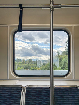 A picturesque view of lush greenery and a cloudy sky seen through the window of a Seattle train. The scene includes trees and cloudy skies.の写真素材