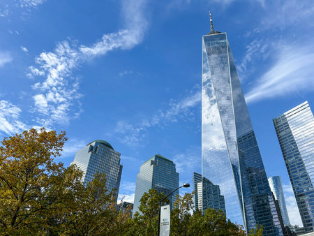 A low-angle view of One World Trade Center and surrounding buildings against a blue sky. Taken at...