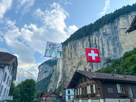 Scenic view of Lauterbrunnen, Switzerland with its iconic waterfalls and charming buildings. Swiss and local flags add to the picturesque atmosphere.の写真素材