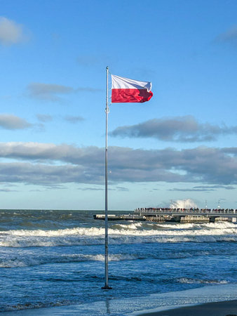 The Polish flag flies proudly on the beach at KoÅ‚obrzeg, with the pier in the background.