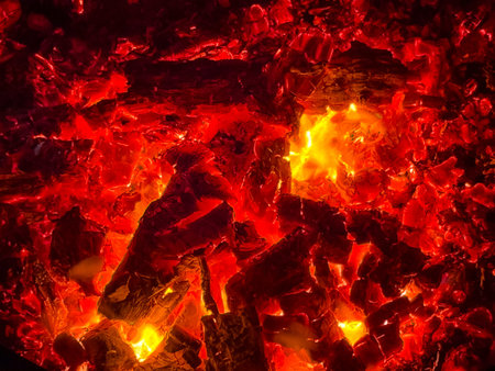 A close-up view of burning embers and glowing ash. The intense heat and vibrant colors create a...