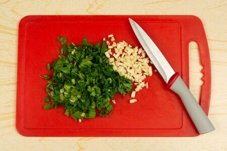 Sliced â€‹â€‹green onions, parsley and dill on a red cutting board. Natural nutrition....