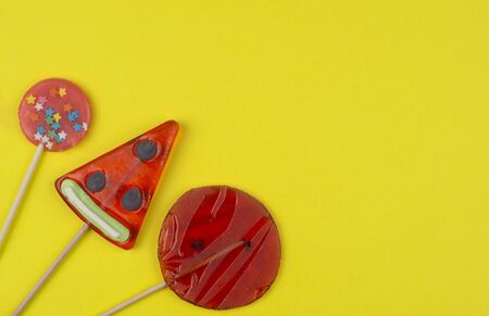 Sweet tasty candy lollipops bright red on a yellow background flat layの写真素材