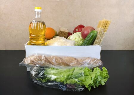 Box with a set of products for delivery. Bread, pasta, salad, cereals, sunflower oil, vegetables,...