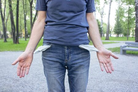 Upset man in blue jeans with empty pockets. The concept of poverty, crisis, falling incomeの写真素材