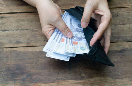 100 dollar banknotes are placed in a gray purse or purse on  wooden