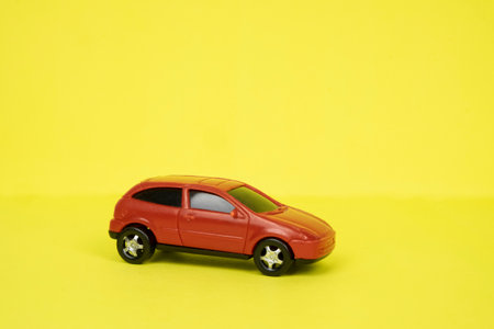 Toy red car close-up on a yellow background. Place for textの写真素材