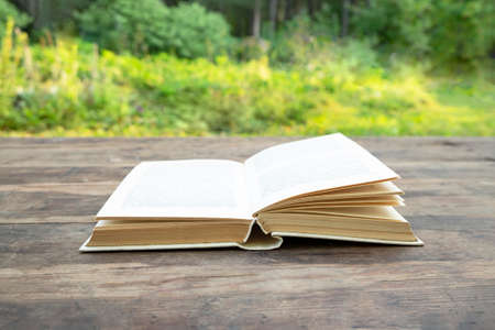 Open book on a wooden table outdoors. Reading concept, classical literatureの写真素材