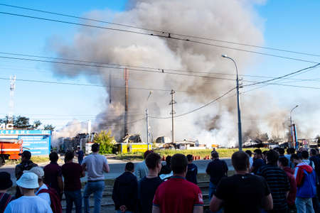 Explosion and fire at a gas station. People look at clouds of thick smoke in the blue sky. Russia, Novosibirsk, June 14, 2021のeditorial素材