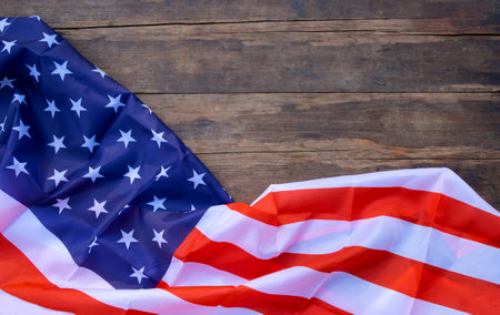 An American flag made of silk is laid out on an old wooden table. flat lay. Place for textの写真素材