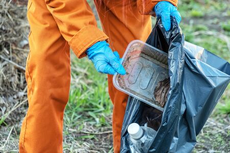 Worker in a suit collects dirty plastic in a park. Garbage cleaning
