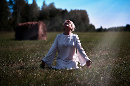 Young woman kneeling with open arms looking to the sky