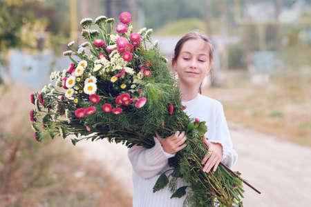 Happy girl walking on the road with flowers in her hands smiling closing her eyesの写真素材