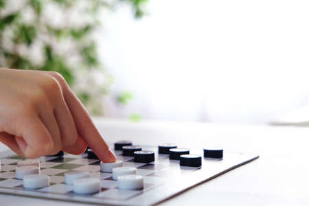 Checkers game. The hand moves the piece across the playing field. Place for textの写真素材